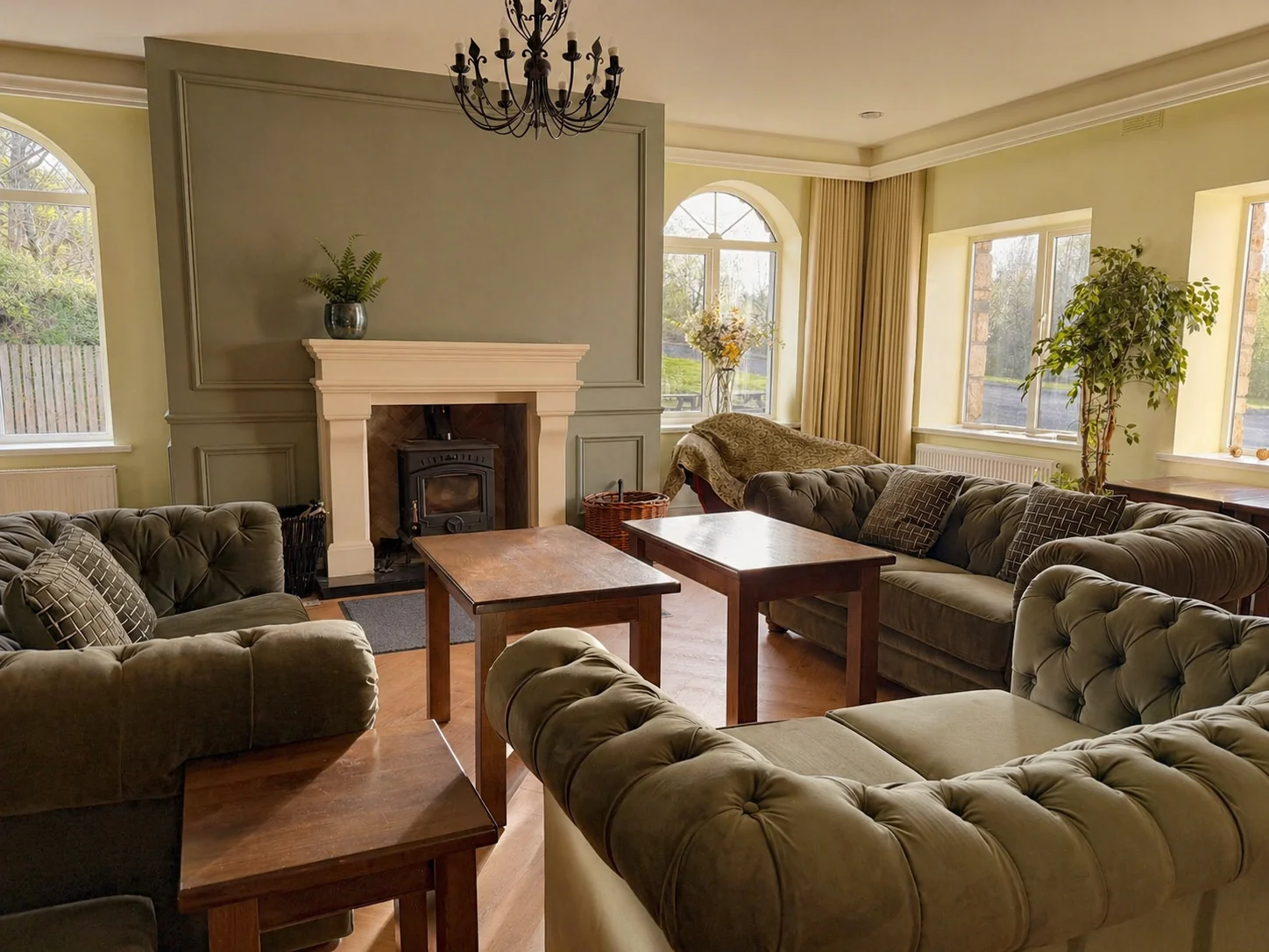 Lounge facing the arched front windows with chesterfield sofas and fireplace at Donegal Manor
